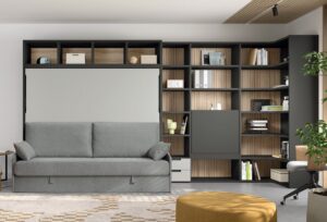 Habitación de invitados con cama abatible, sofá, librería y zona de trabajo